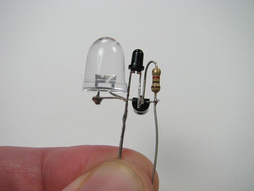 К этому моменту под компонентами торчат только два контакта: один идет к резистору и коллектору (крайнему правому выводу) транзистора, а другой - к эмиттеру фототранзистора и к катоду светодиода
